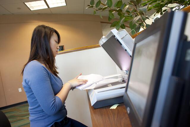 A student uses a document scanner at Alexander Library