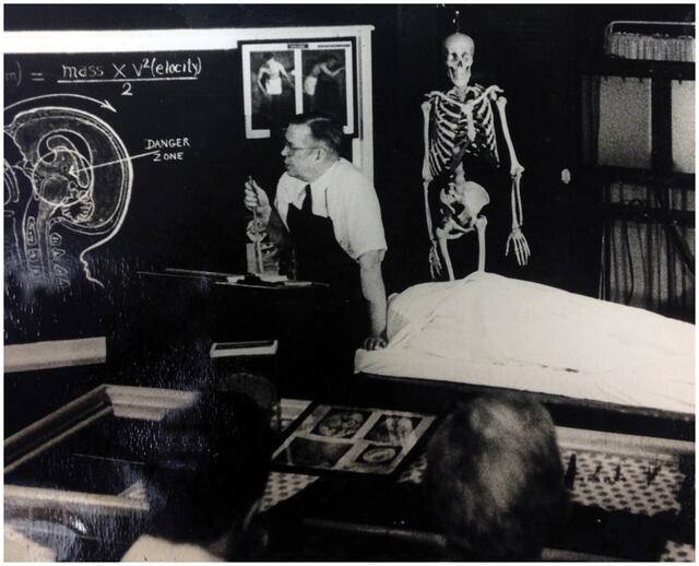 Physician teaching a class, looking at a chalkboard with brain diagram