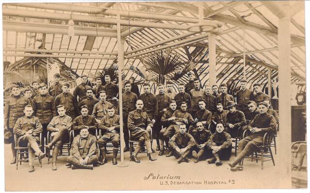 Postcard showing group of standing and seated men inside the Solarium of the US Debarkation Hospital #3