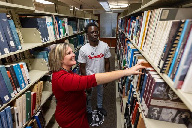 Photo of a Robeson faculty member helping a student find a book from the stacks