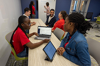 Group of students talking and working together in a library space