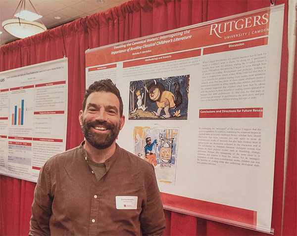 Image of a male graduate student standing in front of a poster presentation