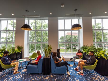 View of new Digital Learning Commons in Alexander Library showing students seated on sofas with window in the background