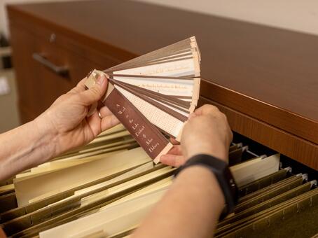 Close up on an archivist's hands while they pull a document out of the drawer
