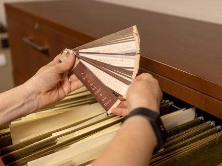 Close up on an archivist's hands while they pull a document out of the drawer