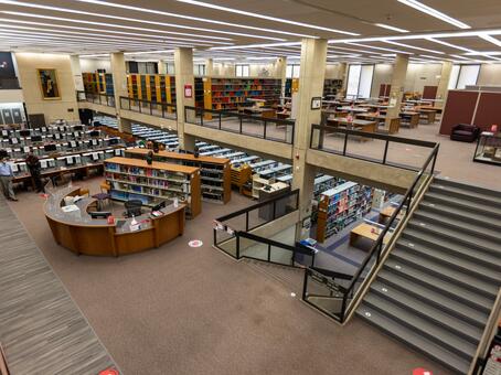 Photo of the main area of the Smith library, featuring computers and book shelving, along with a help desk