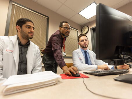 A Smith staff member helping students on the computer in the computer lab from an up-view on the table