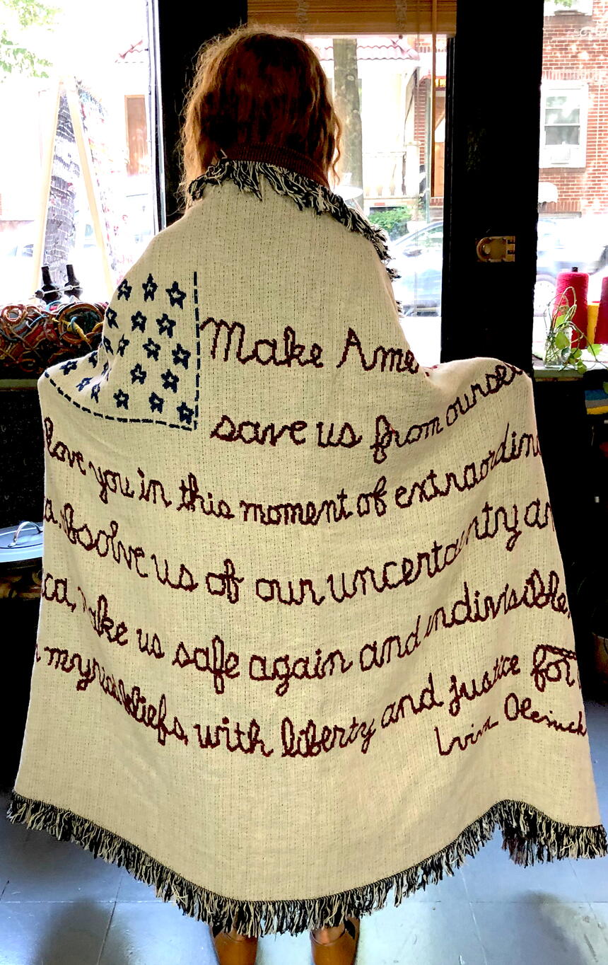 art: standing woman with blanket with embroidery on it..from the back