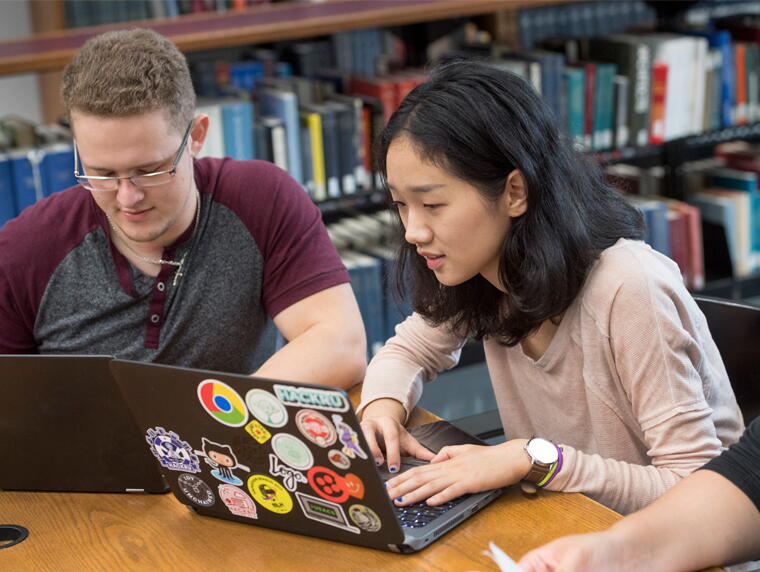 students in library working on laptops