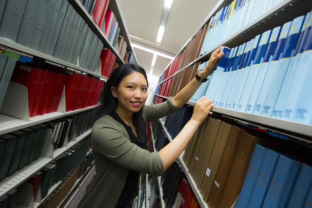 A smiling student searches for a journal in Smith Library's stacks