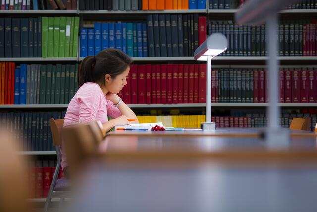 A student studies from a textbook at a table in Smith Library
