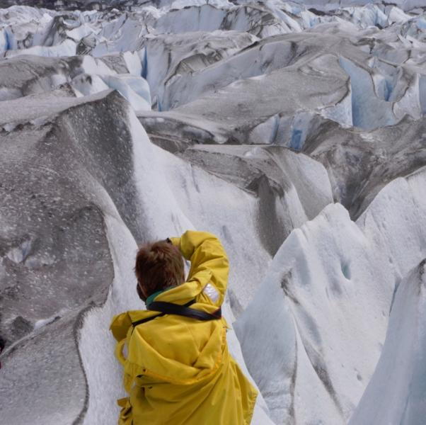 Photo of Ms. Burko's back as she looks over mountains in a yellow coat