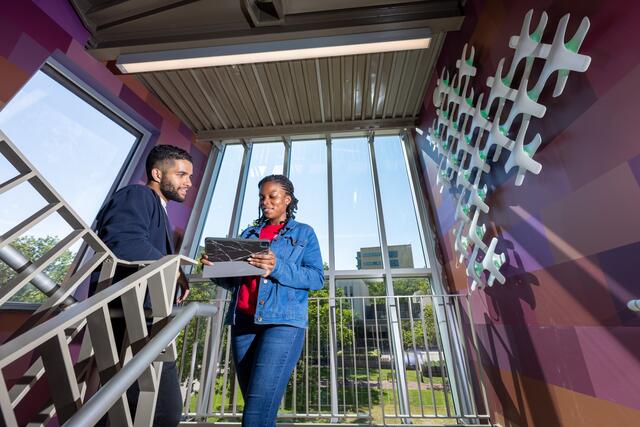 Two students standing in the stairwell of the Dana library