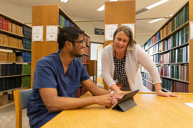 A librarian helps a student studying with his tablet at RWJ Library