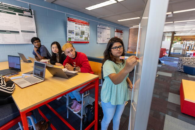 Students using the study space areas in the library of science and medicine, one student is writing on a whiteboard