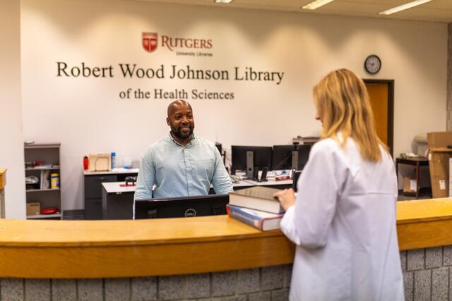 A staff member helps a student at the RWJ circulation desk