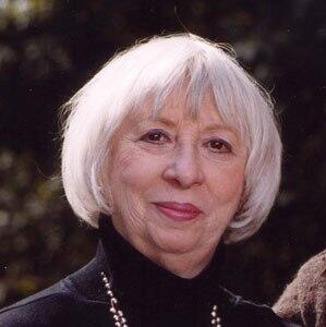 Photo of Janet Indick with short white hair and smiling with her lips closed
