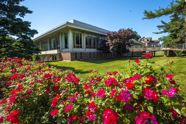 A view of Douglass Library with red flowers in the foreground. Photograph by Nick Romanenko.
