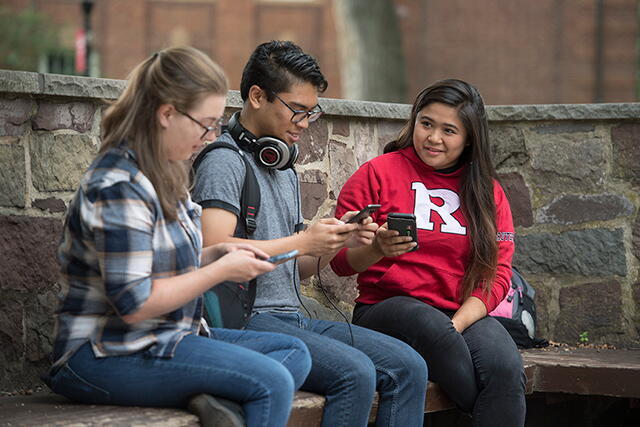 Rutgers students sitting and looking at mobile phones.