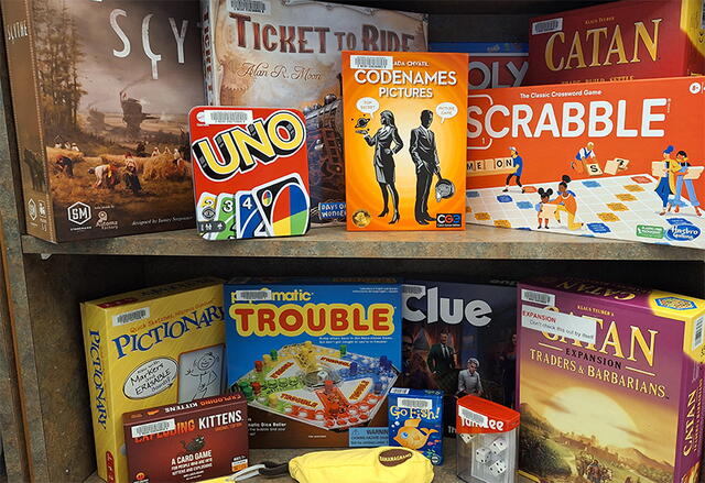Image of board games arranged on two shelves at the Robeson Library Access Services desk.