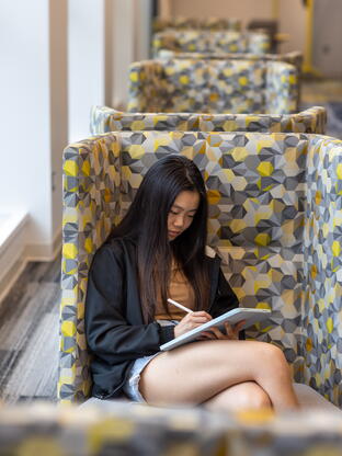 Student using a tablet with a stylus in one of Alexander library's study spaces