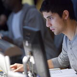 A focused student uses a computer in Douglass Library at night