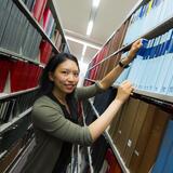 A smiling student searches for a journal in Smith Library's stacks