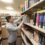 Photo of a Smith faculty member pulling a book from the shelves in Smith library