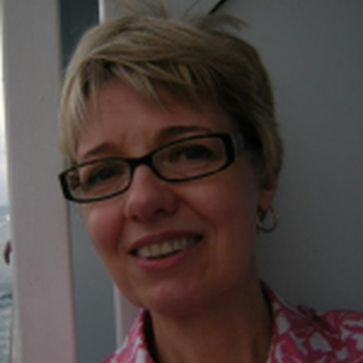 Photo of Rhonda, wearing a pink patterned collared shirt and black glasses