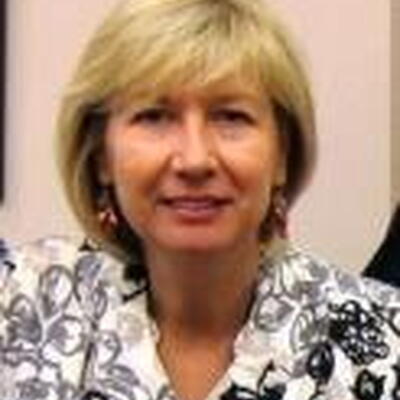 Photo of Elizabeth, wearing a black and white patterned shirt in front of a pink wall