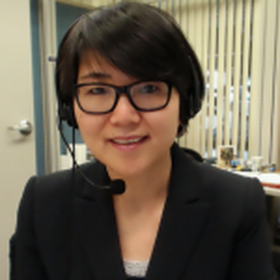 Photo of Yingting, she is wearing a black blazer and glasses and a headset with a microphone in it