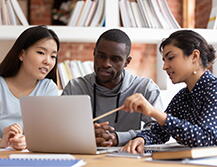 three graduate students looking at a computer